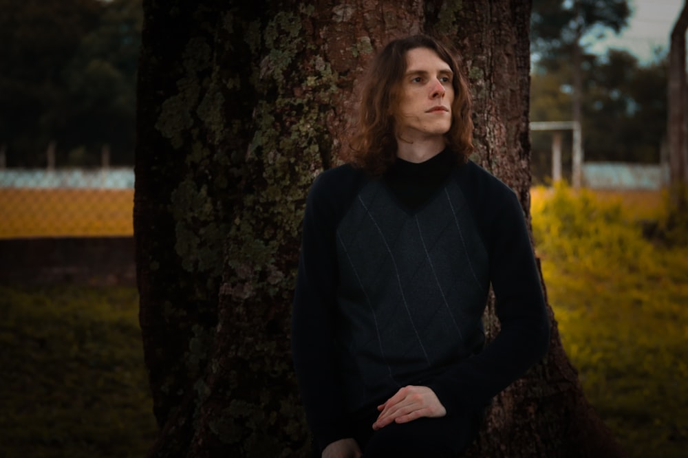 woman in black long sleeve shirt standing beside tree