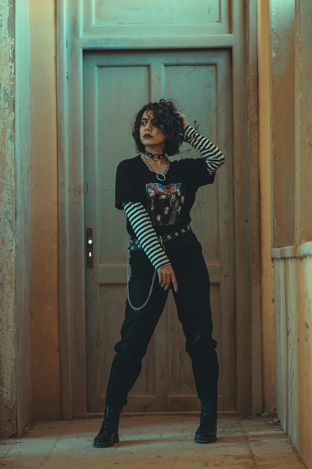 woman in black and white long sleeve shirt and black pants standing beside brown wooden door