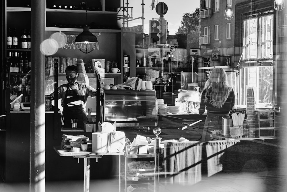 grayscale photo of man and woman standing near table