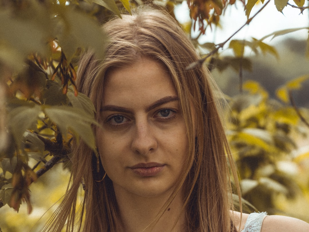 woman in white shirt standing under green tree during daytime