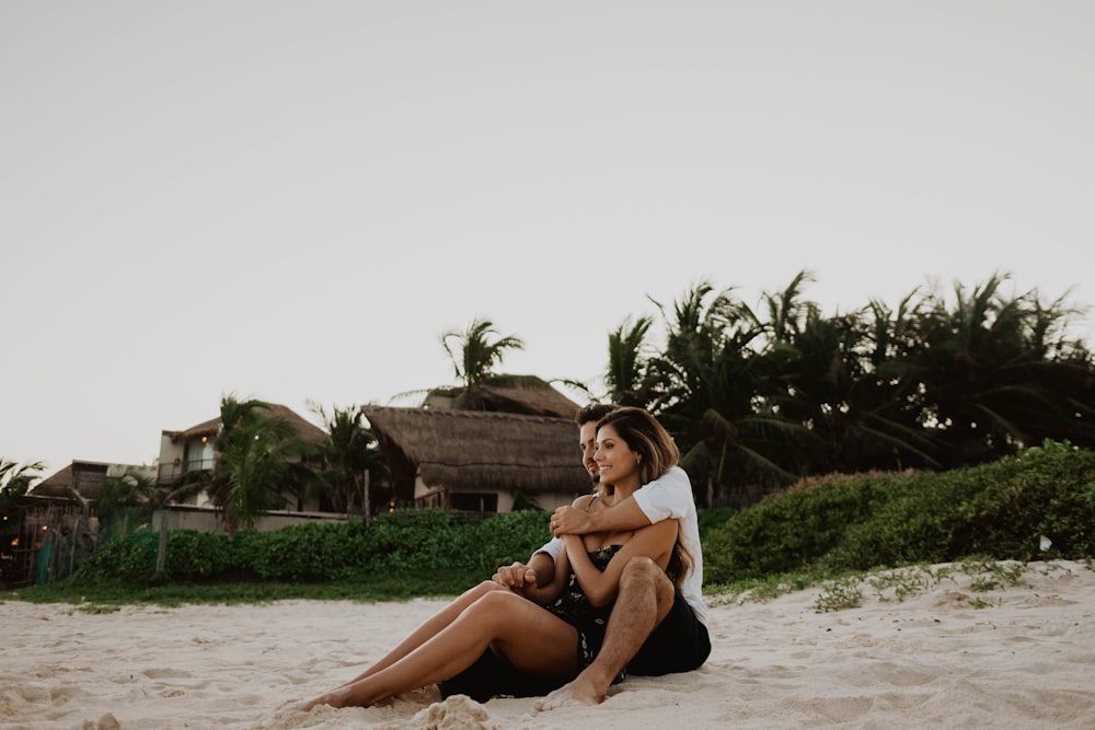 woman in white tank top sitting on white sand during daytime