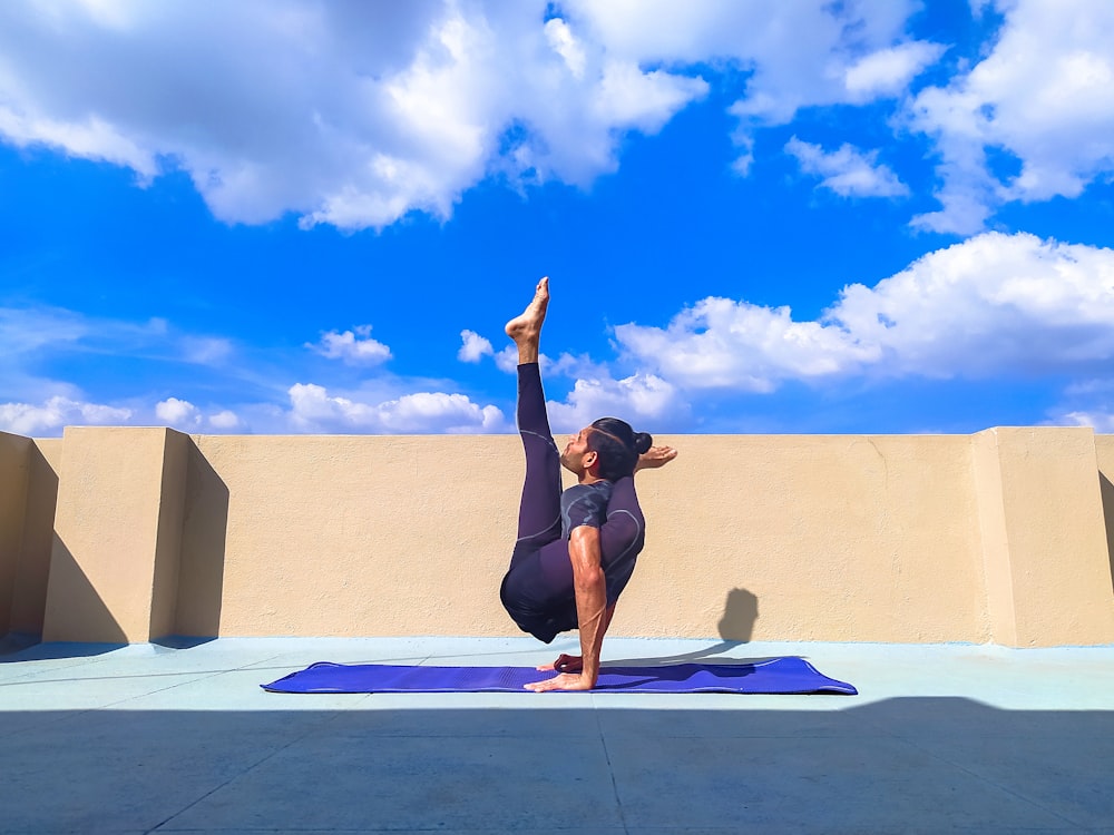 Frau in schwarzem Tanktop und schwarzen Shorts beim Yoga auf blauer Yogamatte