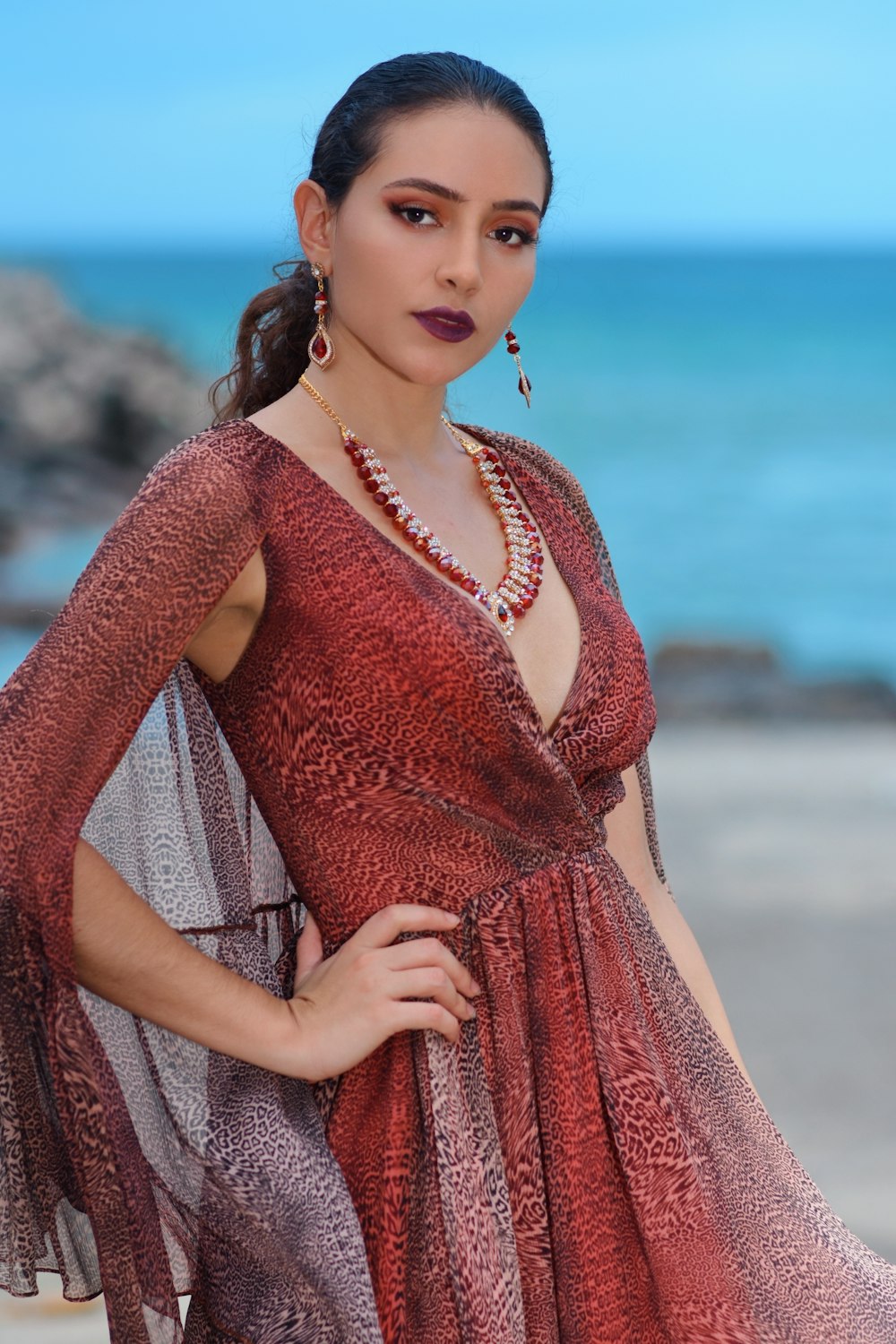 woman in red and brown dress standing on beach during daytime