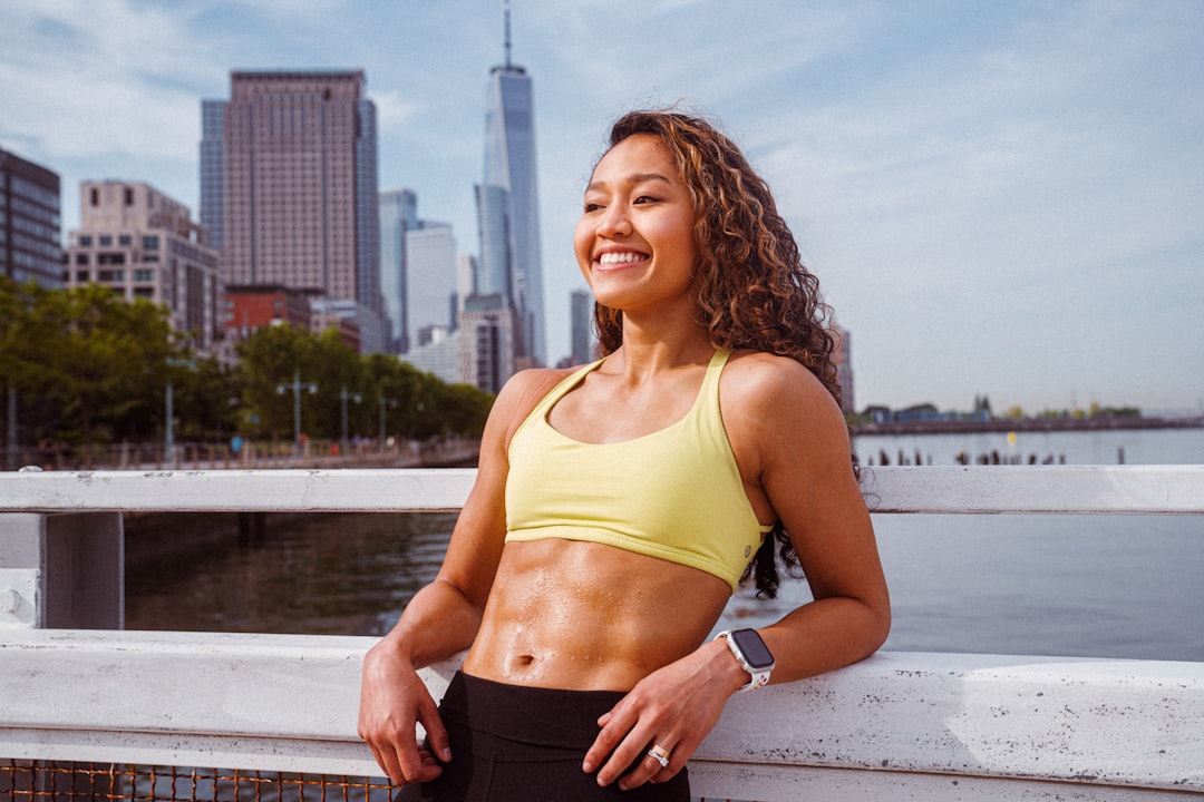 woman in yellow sports bra and black shorts standing near body of water during daytime