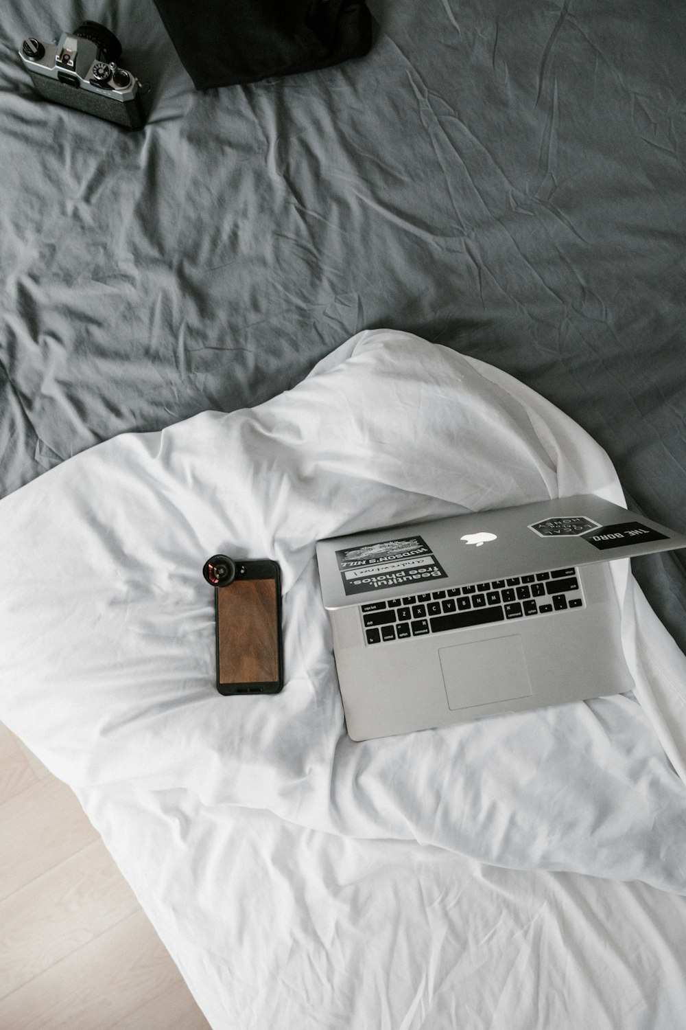 MacBook plateado junto a billetera de cuero marrón sobre textil blanco