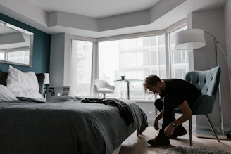 A close-up of a male athlete tying running shoes in a minimalist training space.