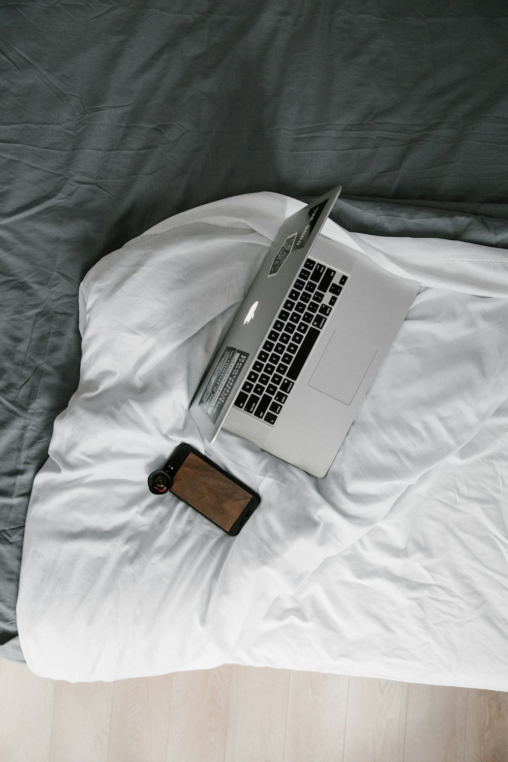 MacBook Pro accanto al portafoglio in pelle marrone sul letto bianco