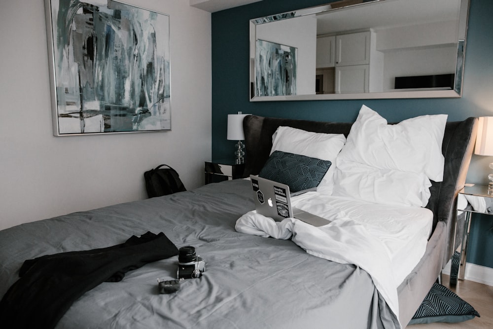 black laptop computer on white bed