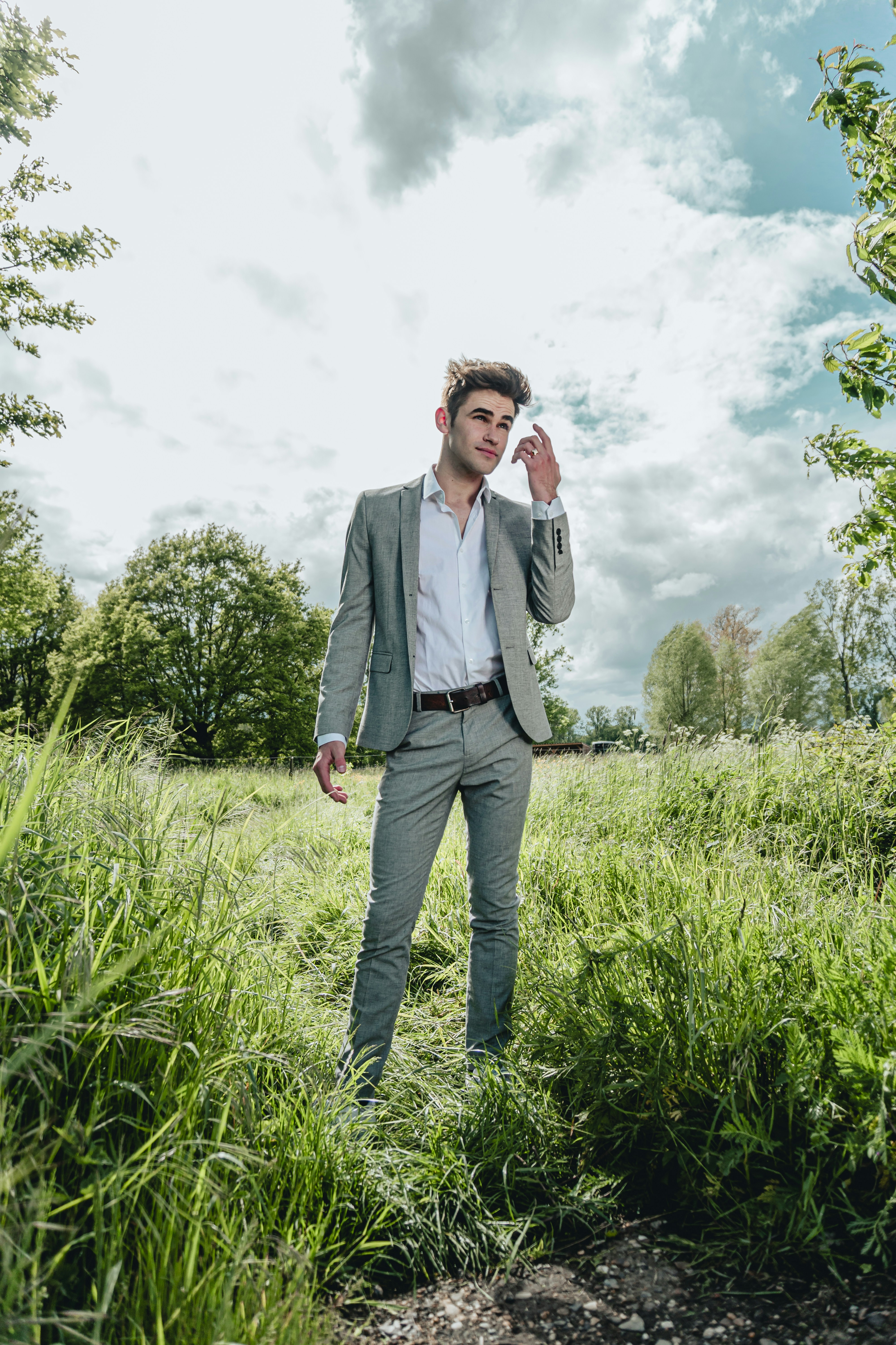 man in gray suit jacket standing on green grass field during daytime