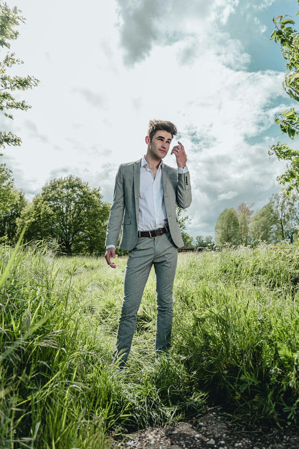 man in gray suit jacket standing on green grass field during daytime