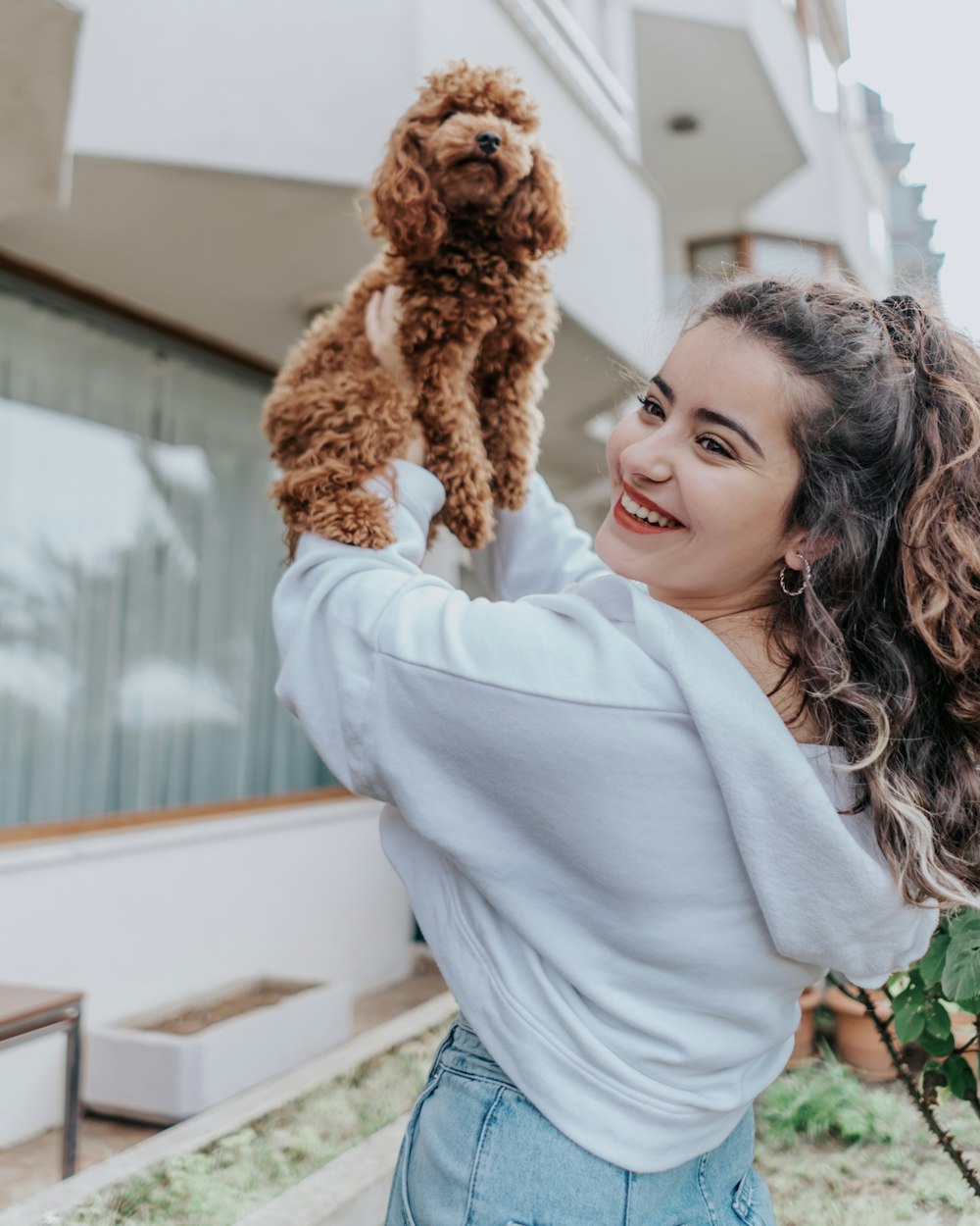 woman in white long sleeve shirt holding brown dog