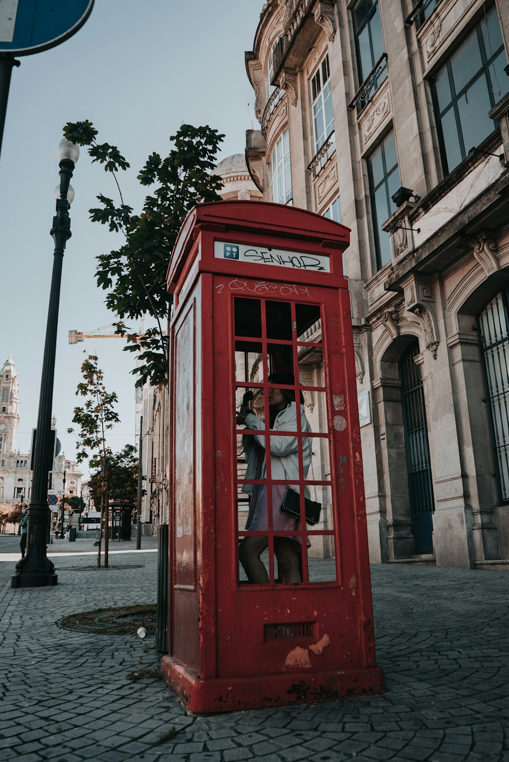 red telephone booth near brown concrete building during daytime