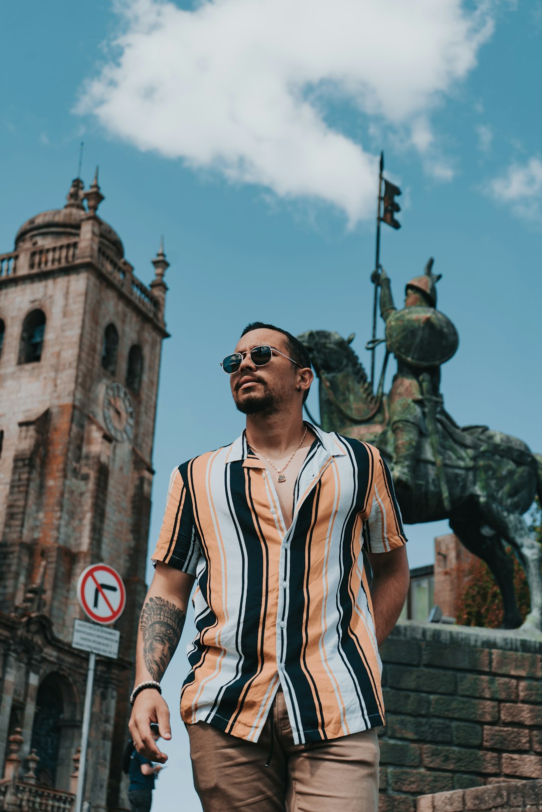 man in black sunglasses and white and black stripe shirt standing near brown concrete building during