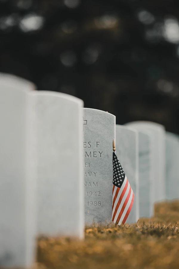 Small flags set at headstones on bright grass