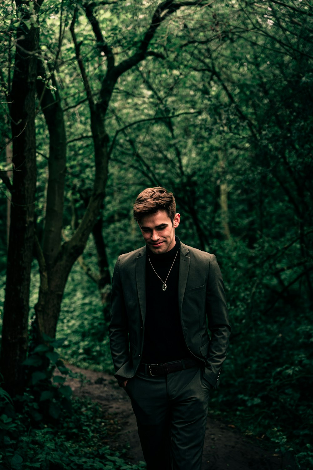 낮 동안 숲에 서 있는 검은 양복 재킷을 입은 남자
