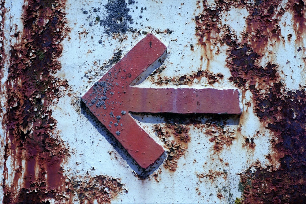 Signe de flèche rouge sur un mur de béton blanc et brun