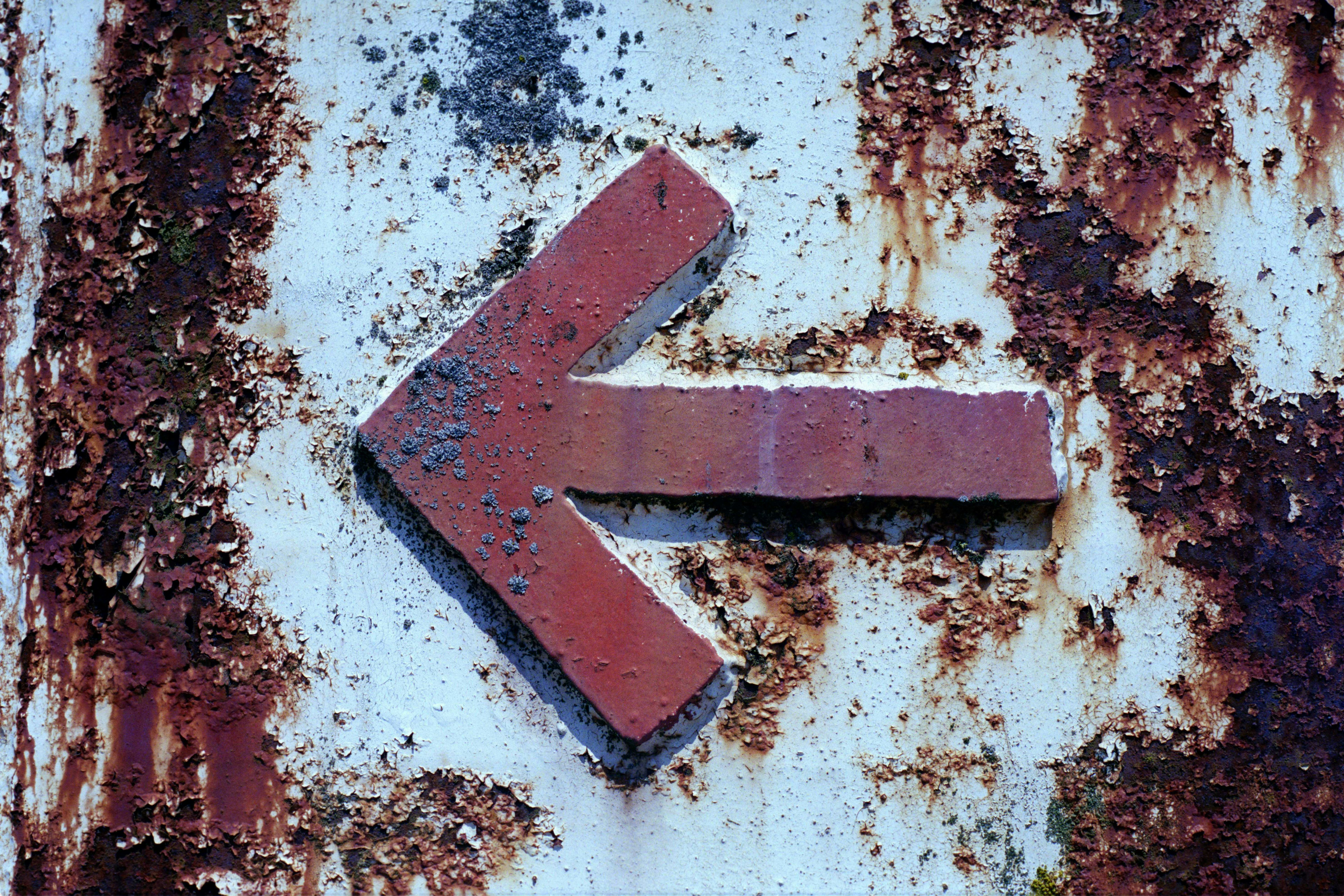 red arrow sign on white and brown concrete wall