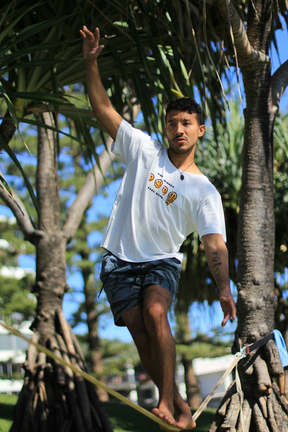 man in white crew neck t-shirt and black shorts standing near green trees during daytime