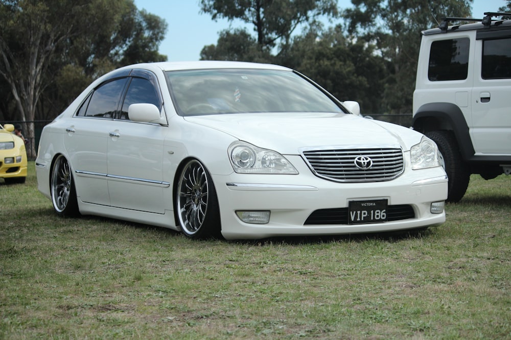 white mercedes benz sedan on green grass field during daytime