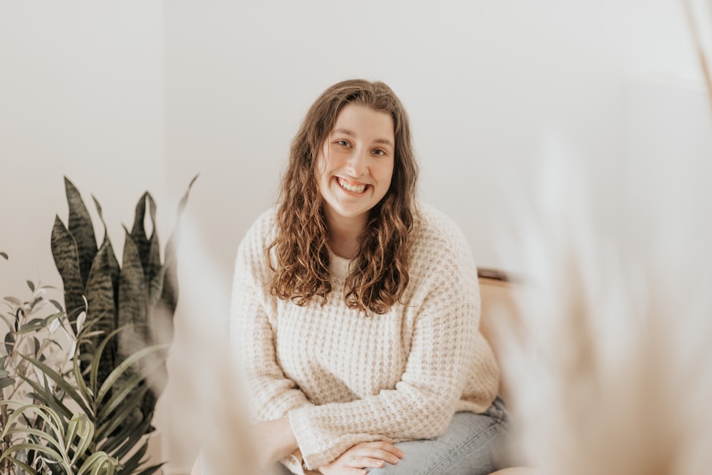 woman in white knit sweater sitting on floor