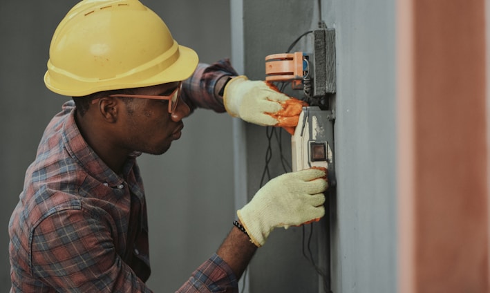 man in brown hat holding black and gray power tool