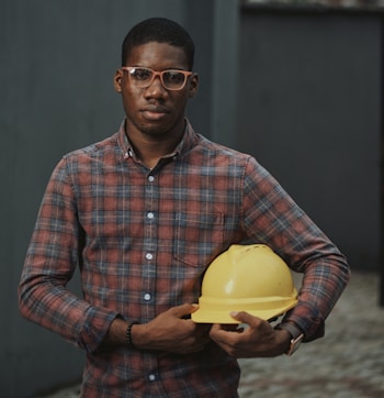 man in blue red and white plaid dress shirt holding yellow plastic bowl