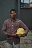 man in blue red and white plaid dress shirt holding yellow plastic bowl