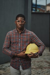 man in blue red and white plaid dress shirt holding yellow plastic bowl
