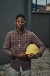 man in blue red and white plaid dress shirt holding yellow plastic bowl