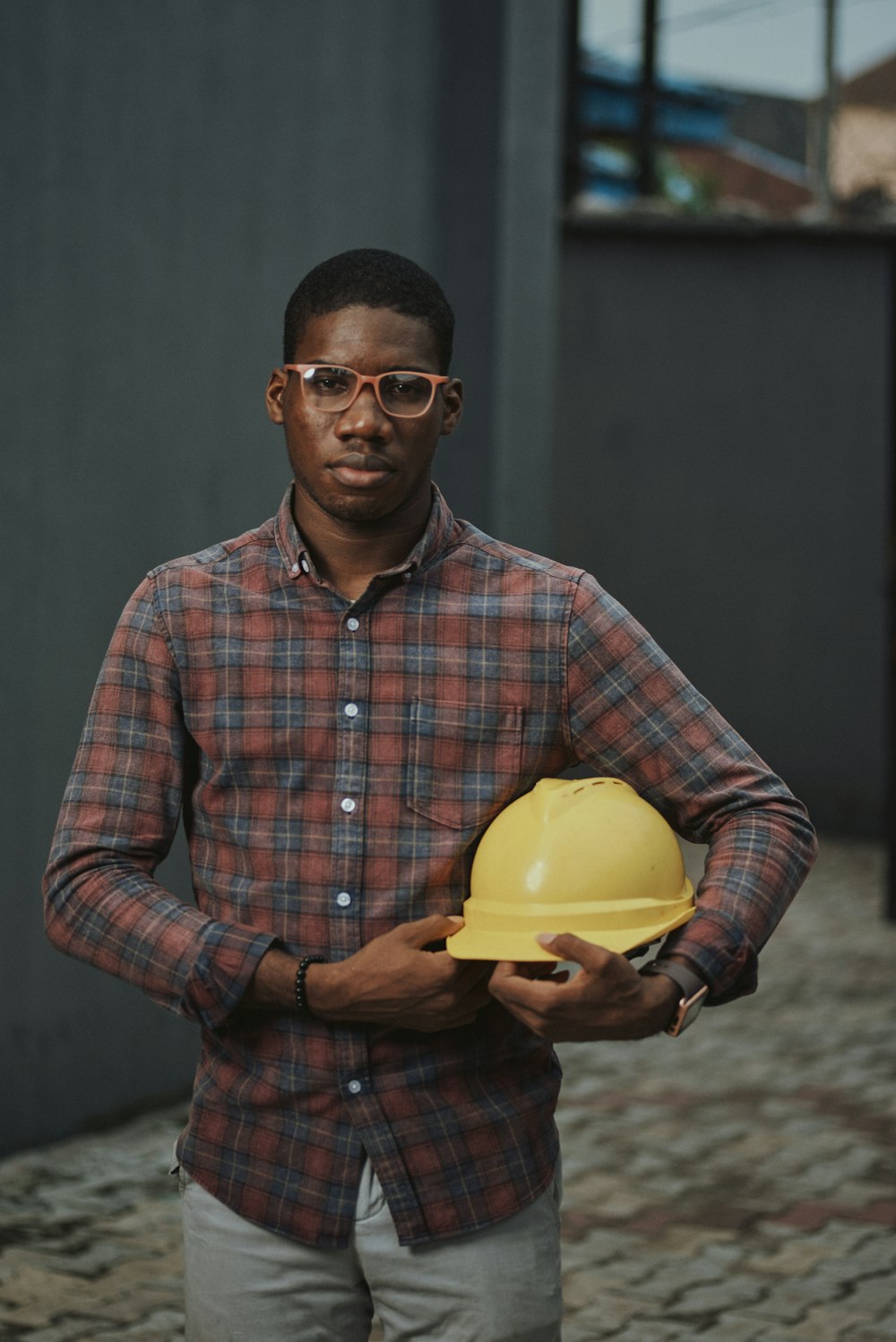 Homme en chemise à carreaux bleu rouge et blanc tenant un bol en plastique jaune