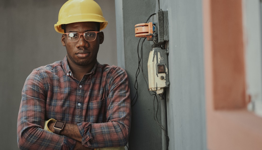 man in blue white and red plaid button up shirt wearing yellow hard hat holding black