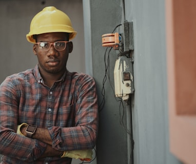 man in blue white and red plaid button up shirt wearing yellow hard hat holding black