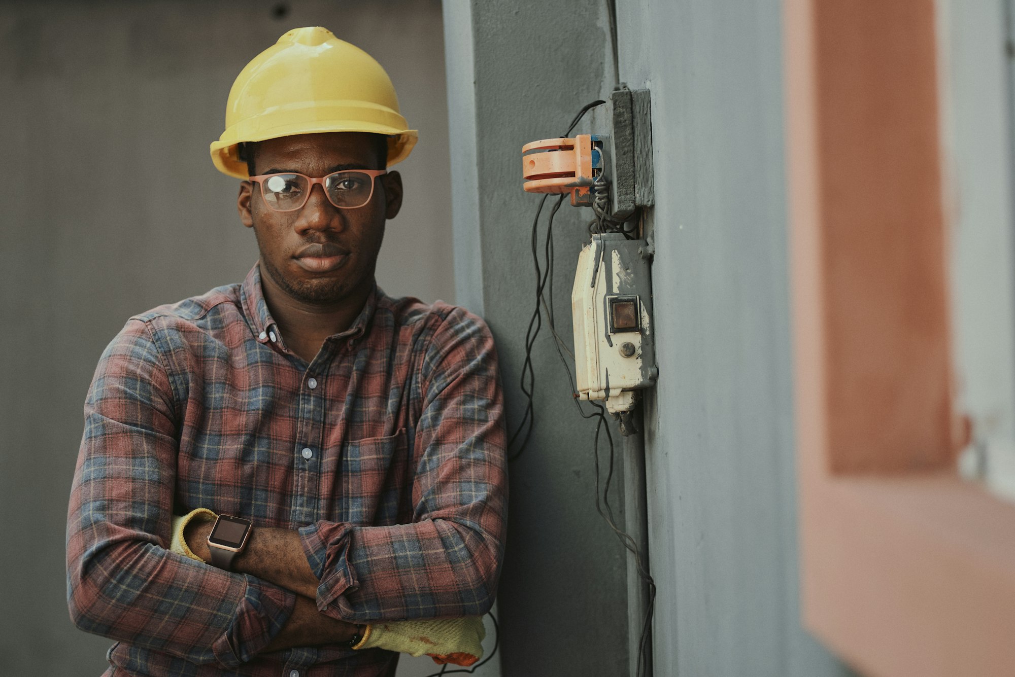 Portrait of a black man architect at a building site looking at camera. Confident civil engineering wearing a hardhat and eye goggles. Successful mature civil engineer at a construction site with open