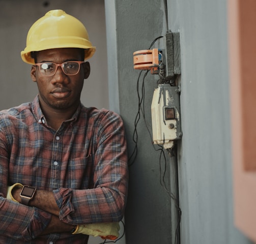 man in blue white and red plaid button up shirt wearing yellow hard hat holding black