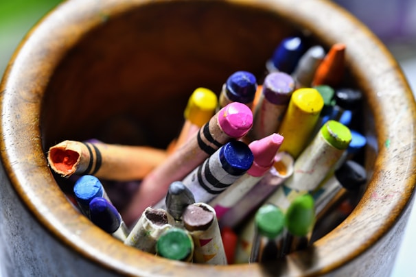 assorted color coloring pencils in brown wooden bucket