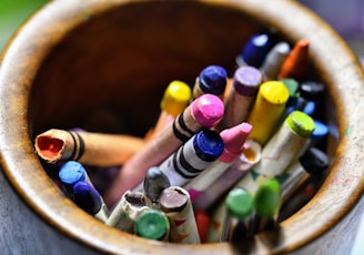 assorted color coloring pencils in brown wooden bucket