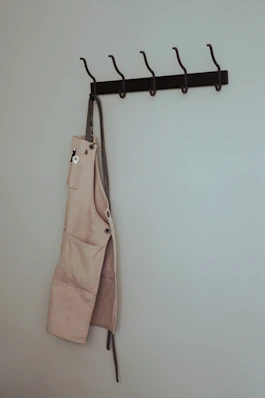 brown leather sling bag hanged on black clothes hanger