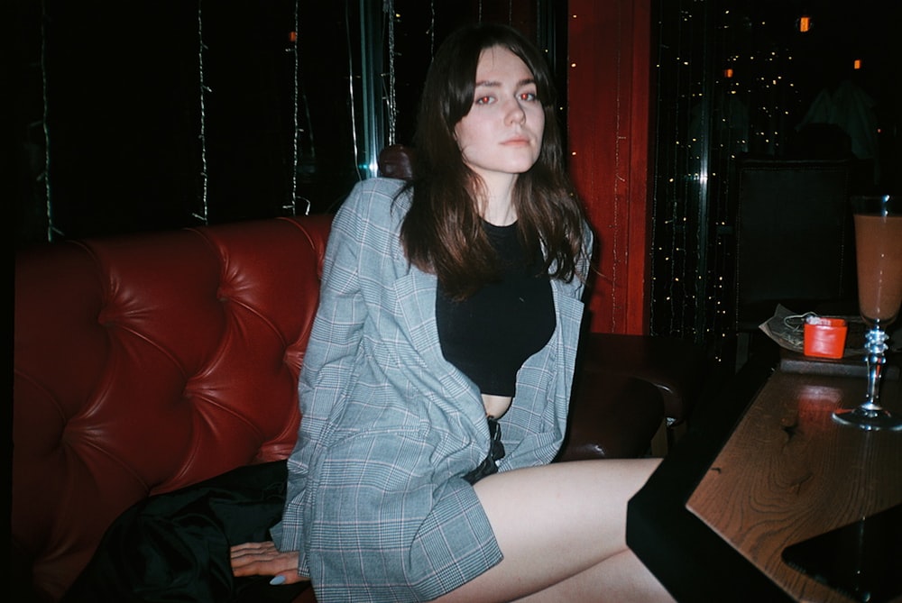 woman in black shirt and gray cardigan sitting on red leather couch