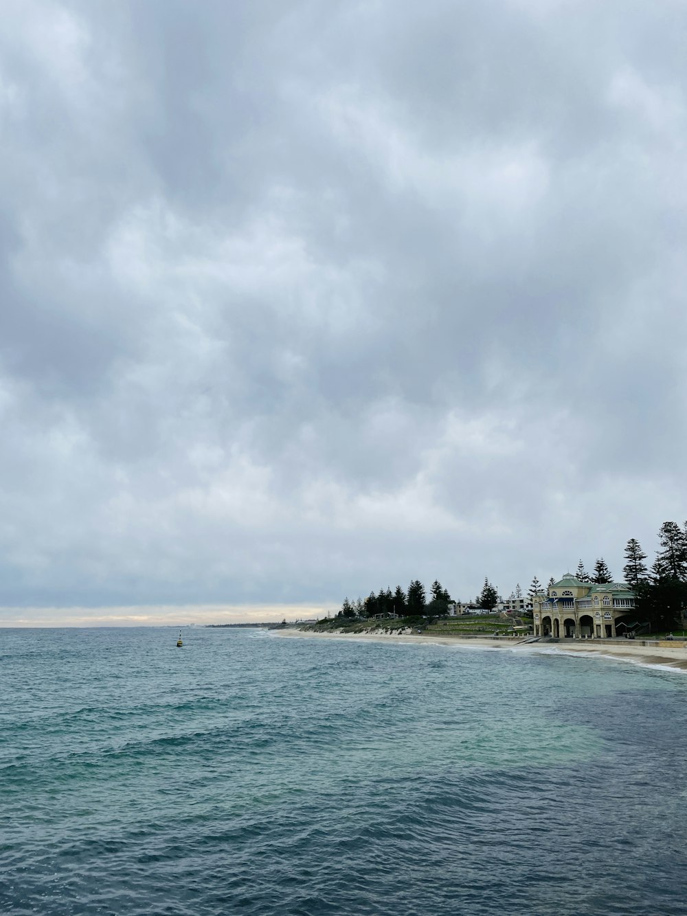 green trees near body of water under white clouds and blue sky during daytime