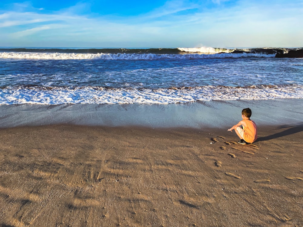 femme en bikini noir assis sur le rivage de la plage pendant la journée