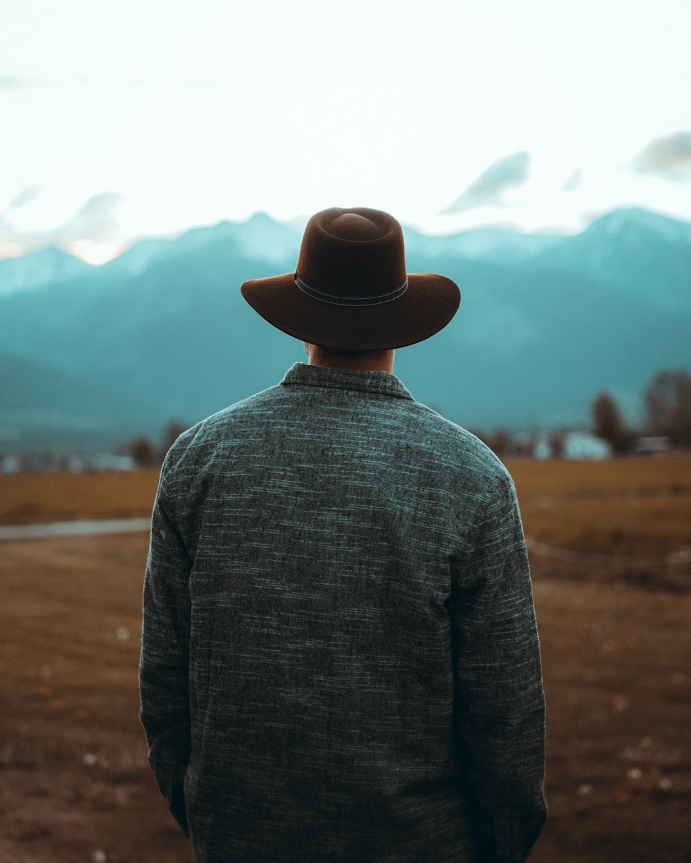Foto hombre con suéter gris y sombrero fedora negro parado en un campo  marrón durante el día – Imagen Montana gratis en Unsplash
