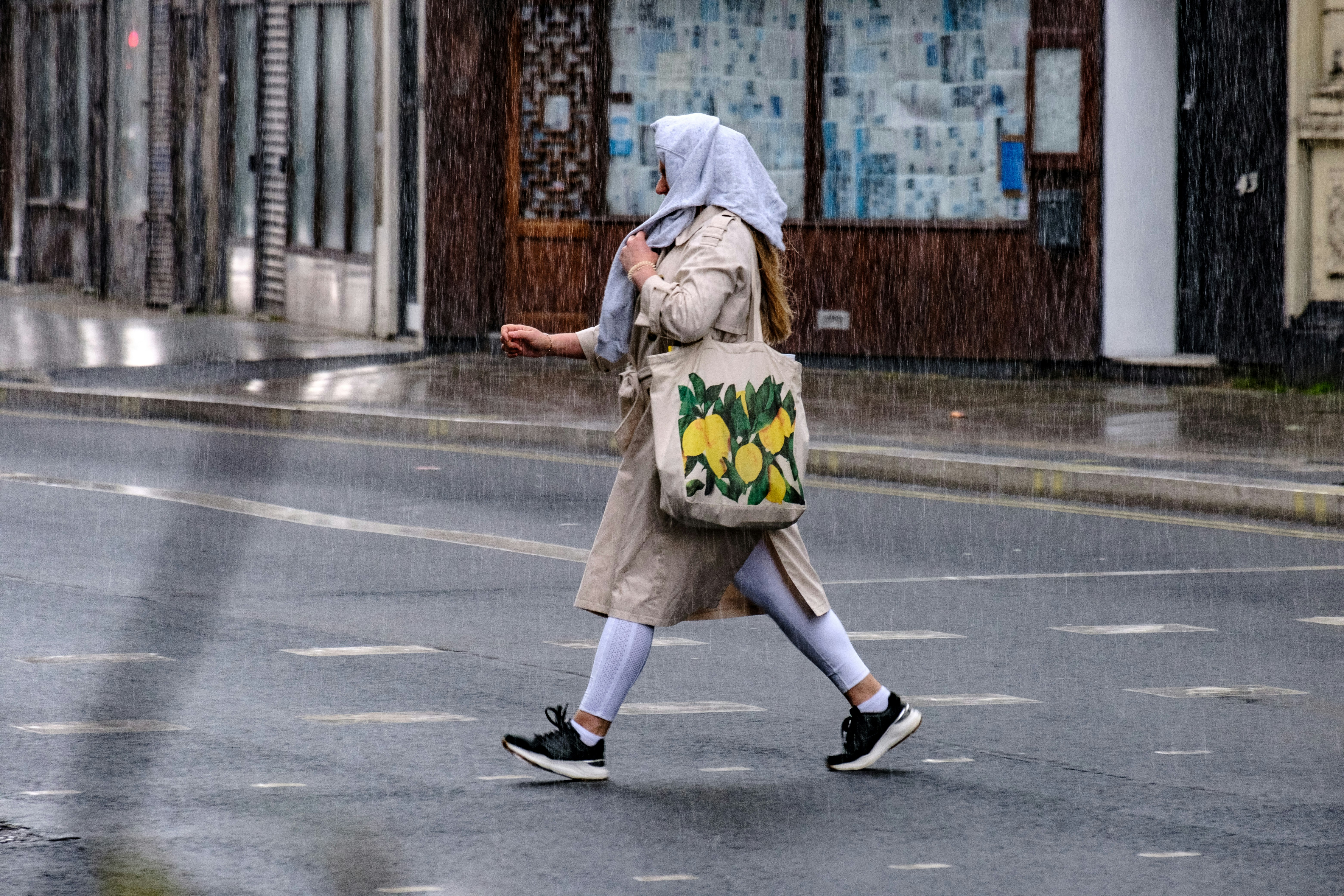 woman in brown coat walking on sidewalk during daytime