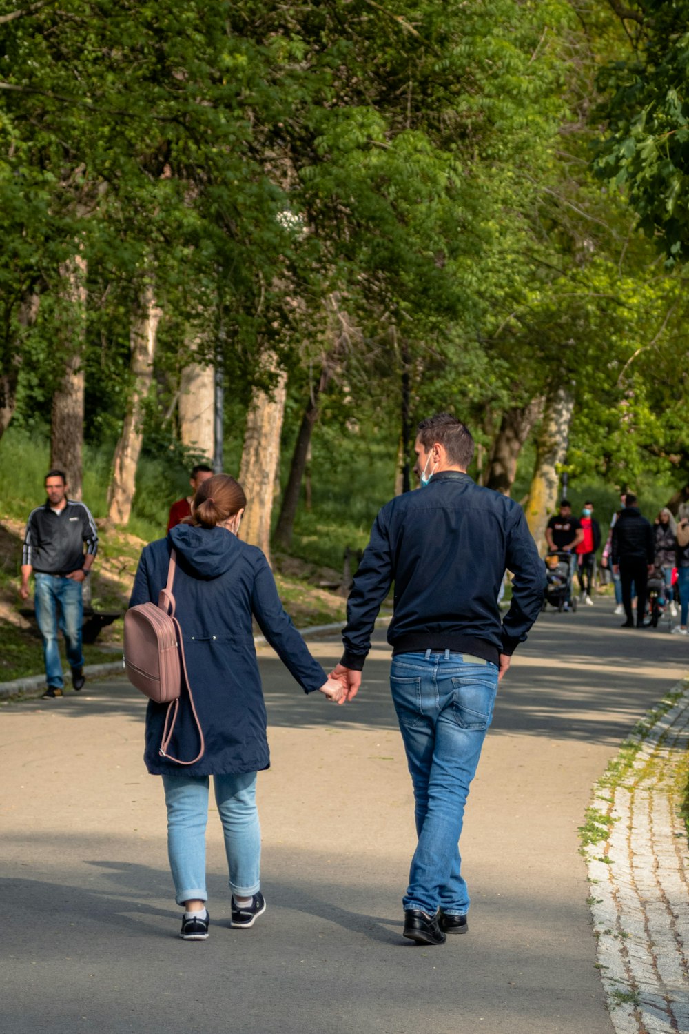 man in black jacket and blue denim jeans walking on street during daytime