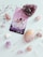 A tarot card titled '3 of Cups' is surrounded by various gemstones and crystals including amethyst, quartz, and rose quartz. The card features three women in white dresses embracing each other against a starry sky. Lavender sprigs are scattered around for decoration.