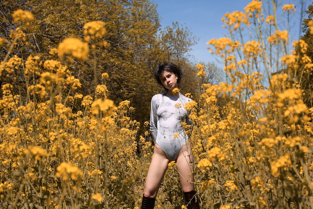 woman in white long sleeve shirt and black shorts standing on yellow flower field during daytime