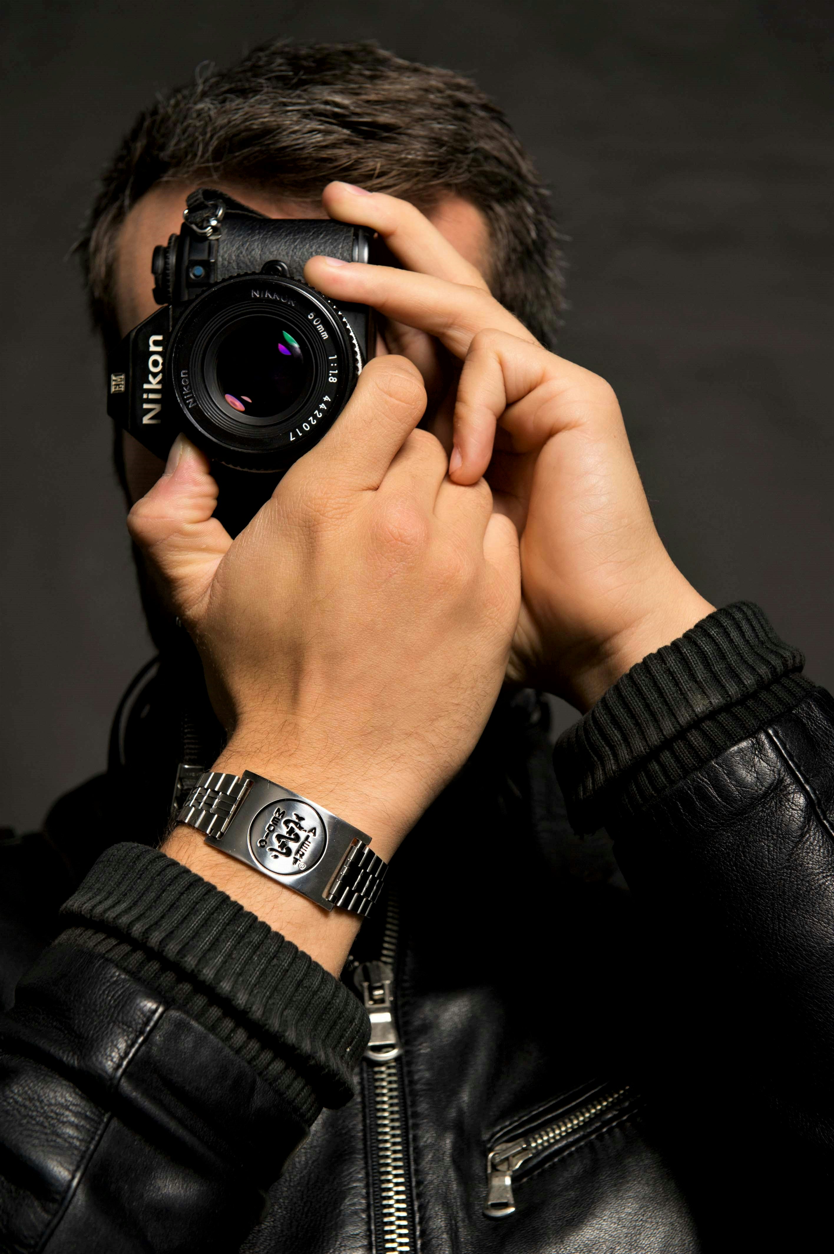 A man takes a self portrait with a nikon camerawhile wearing a MedicAlert bracelet.