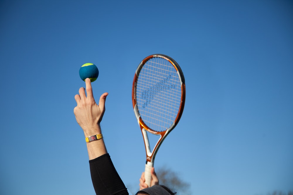 person holding red and white tennis racket