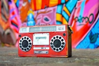 A colorful boombox with built-in speakers and cassette deck on a picnic blanket.