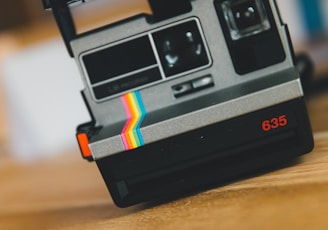 black polaroid instant camera on brown wooden table