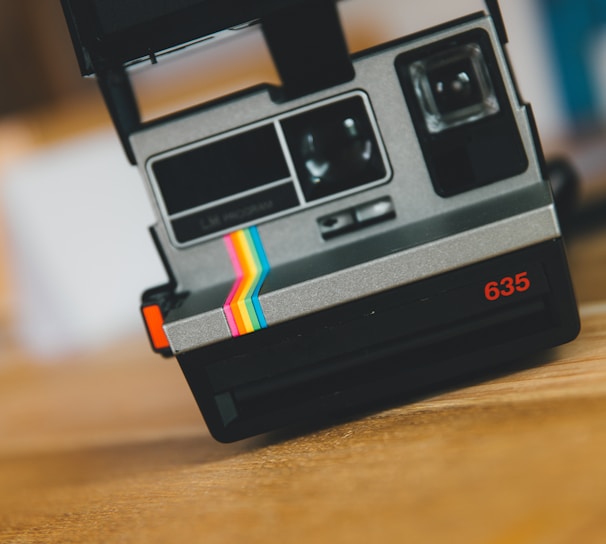 black polaroid instant camera on brown wooden table